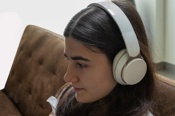 young teenage girl concentrating on listening to music with white bluetooth headset