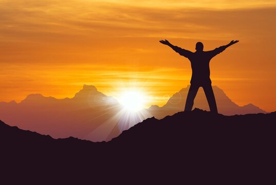 Man standing on top of mountain arms raised successfully