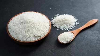 Rice grains in wooden bowl isolated black background.