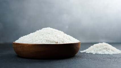Rice grains in wooden bowl isolated black background. Straight on angle.