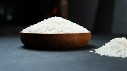 Rice grains in wooden bowl isolated black background.