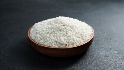 Rice grains in wooden bowl isolated black background.