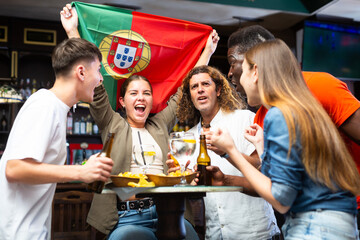 Fans with the flag of Portugal celebrate the victory of their favorite team in a beer bar