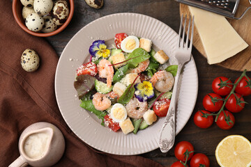 Delicious Caesar salad with shrimps and ingredients on wooden table, flat lay