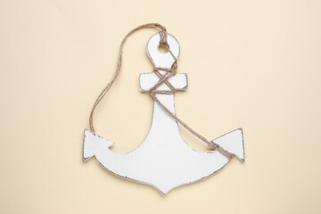 White anchor with hemp rope on beige background, top view