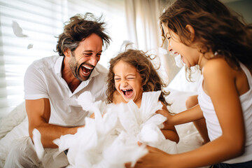Beautiful young family having a pillow fight in the bedroom and enjoying quality time together, fun family bonding - obrazy, fototapety, plakaty