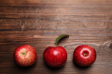 Ripe red apples on wooden table, flat lay. Space for text