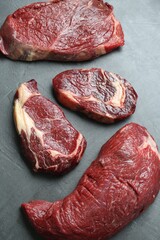Pieces of raw beef meat on grey table, above view