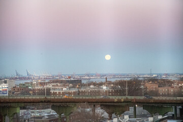 The Moon sets behind the elevated portion of the Brooklyn Queens Expressway BQE as seen from a...