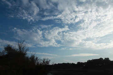 Fototapeta premium White Clouds In Blue Sky Over Silhouetted Landscape
