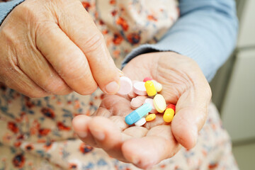 Asian elderly woman holding pill drug in hand, strong healthy medical concept.