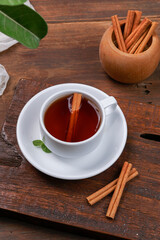 a cup of tea and cinnamon with a dark mode theme on a brown wood background