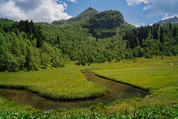 View from the tourist trail to the Dukka Lakes to the valley of the Malaya Dukka River, surrounded by the mountains of the North Caucasus on a sunny summer day, Arkhyz, Karachay-Cherkessia, Russia © Ula Ulachka