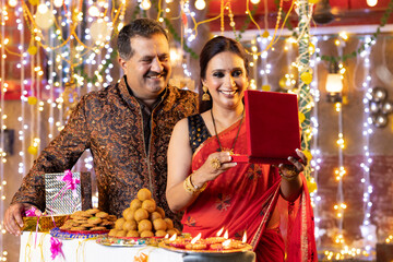 Happy man with surprise gift for wife on the occasion of festival celebration