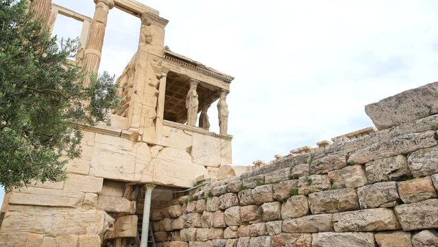 Erechtheion caryatid temple ruins building with marble columns at Athens Greece Acropolis hill, wide angle view of olive tree