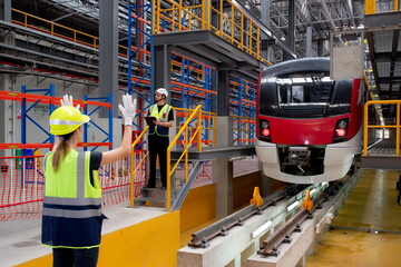 Young caucasian engineer woman or worker signal while engineer man checking electric train for...