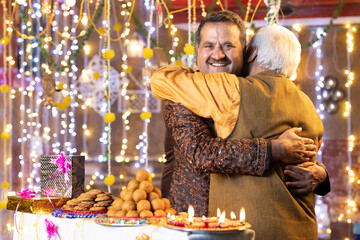 Elderly father embracing adult son on occasion of Diwali festival