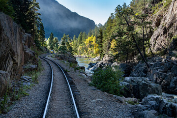 landscape view of railroad tracks traveling through the Colorado mountains on an autumn day along...