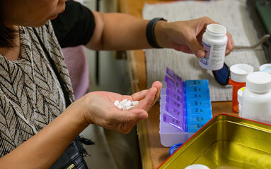 Woman sorting pills into medical pill boxes.