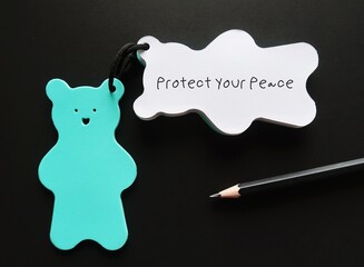 Bear notebook on black background with pencil and handwritten text PROTECT YOUR PEACE, concept of...