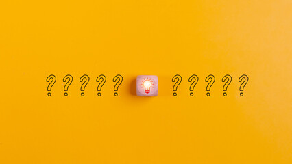 Wooden blocks with question marks and light bulb icons on a yellow background for disruption of...