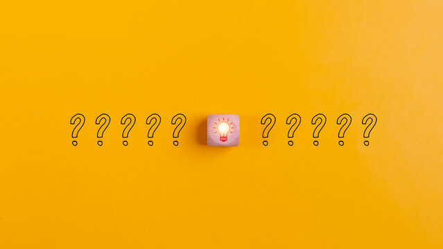 Wooden blocks with question marks and light bulb icons on a yellow background for disruption of problem-solving ideas and creative innovation concepts.