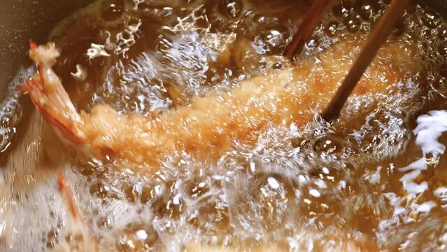 食用油で揚げてるエビフライ。上下を返す動画。