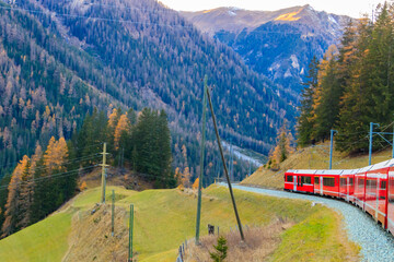 Red passenger train on Rhaetian railway in Canton Graubunden, Switzerland at autumn