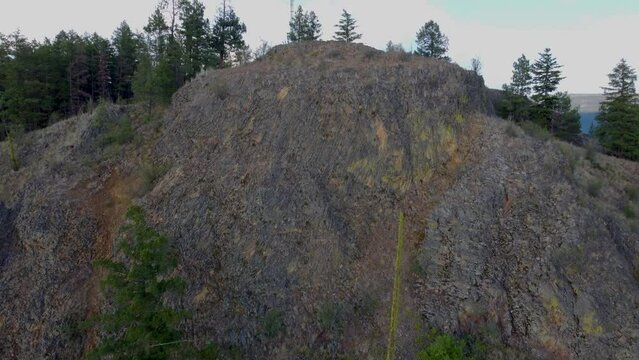 Sheer Cliff Face at the top viewpoint of Spion Kop Mountain in Lakecountry British Columbia. West facing slope featuring cracked shale rock. Drone Flies up and then looks down.