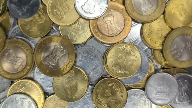 closeup of a pile of one, two, five and ten rupee coins of india made of gold and silver colored metals