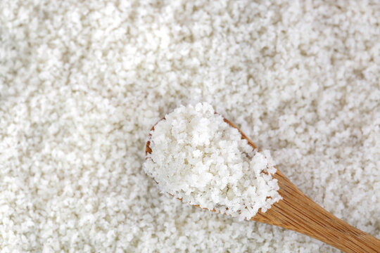 Closeup of unionized salt flakes on wooden spoon. Selective focus of Austrian gourmet salt from Alps mountain showing crunchy texture