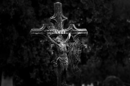 Cross with spider web in cemetery. Halloween background