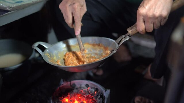 Kerak Telor is a traditional food from Jakarta made from duck egg mixed with sticky rice grated coconut. The seller is cooking egg crust or kerak telor in a small wok with a charcoal stove. 