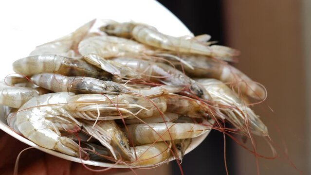 someone holds a bag of shrimp, and there is a pile of shrimp on a plate