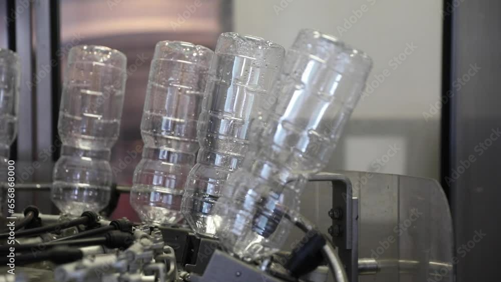 Poster empty plastic bottles upside down after being cleaned and washed rotating on a machine at a vinegar 