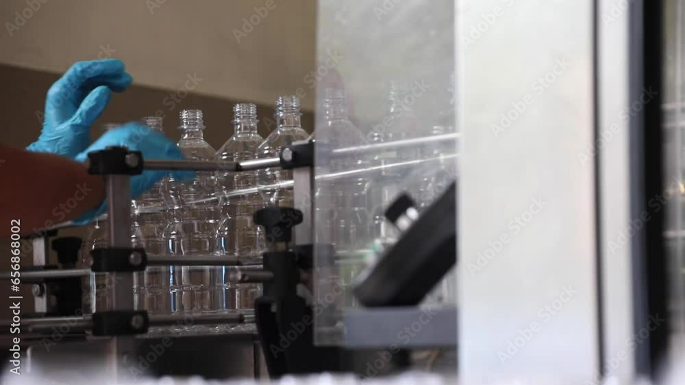 Poster worker places plastic empty bottles onto conveyor belt line for preparation to be filled with vinega