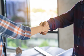 Successful deal, male architect shaking hands with client in construction site after confirm blueprint for renovate building.