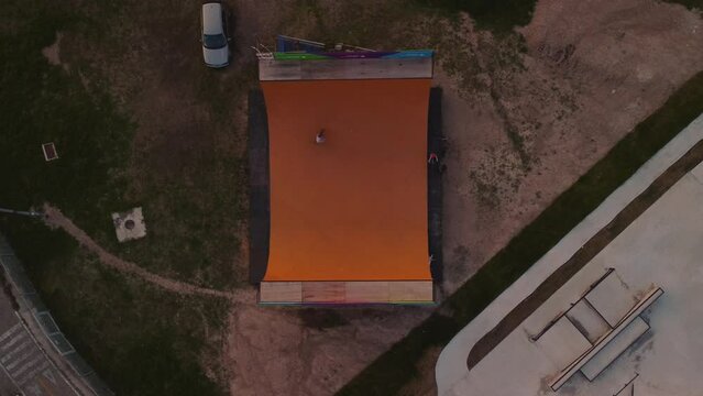 Bmx rider riding on an orange halfpipe ramp, top view