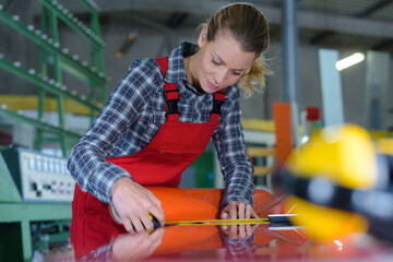 female worker measuring finished metal-plastic object