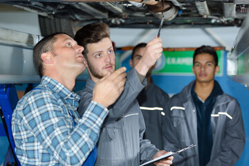 apprentice mechanic and mentor under the car