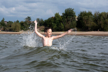happy boy jumping in the waves, splashing in the water, splashing