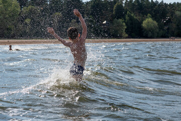 happy boy jumping in the waves, splashing in the water, splashing