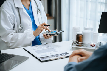 Healthcare costs and fees concept.Hand of smart doctor used a calculator and smartphone, tablet for medical costs at hospital - obrazy, fototapety, plakaty