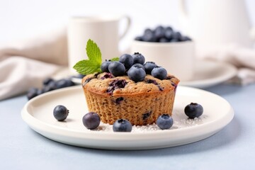 blueberry muffin on a white plate with blueberries scattered around