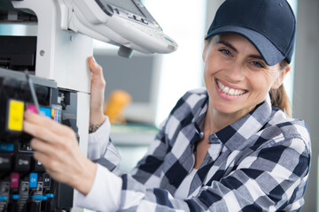woman with screwdriver examining photocopier