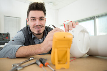 young electrician measuring voltage in fuse board