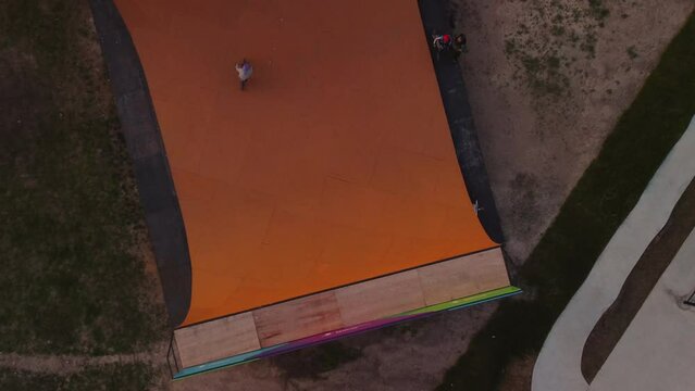 Close-up of a BMX rider riding on a half-pipe ramp in a skate park, top view, zoom in