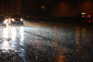 Samochód wieczorem jedzie w czasie ulewy jezdnią. © DarSzach