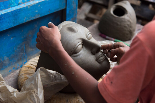 An unknown artist creating clay face of Goddess Durga with use of selective focus 