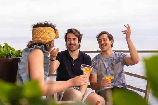 Happy friends drinking cocktails on a roof with sea views - Powered by Adobe
